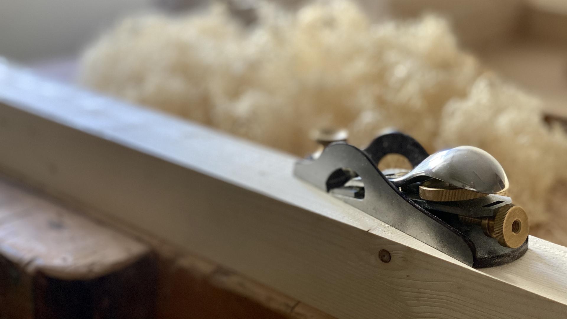 Handhobel Hobel auf Holzbalken, Späne im Hintergrund
